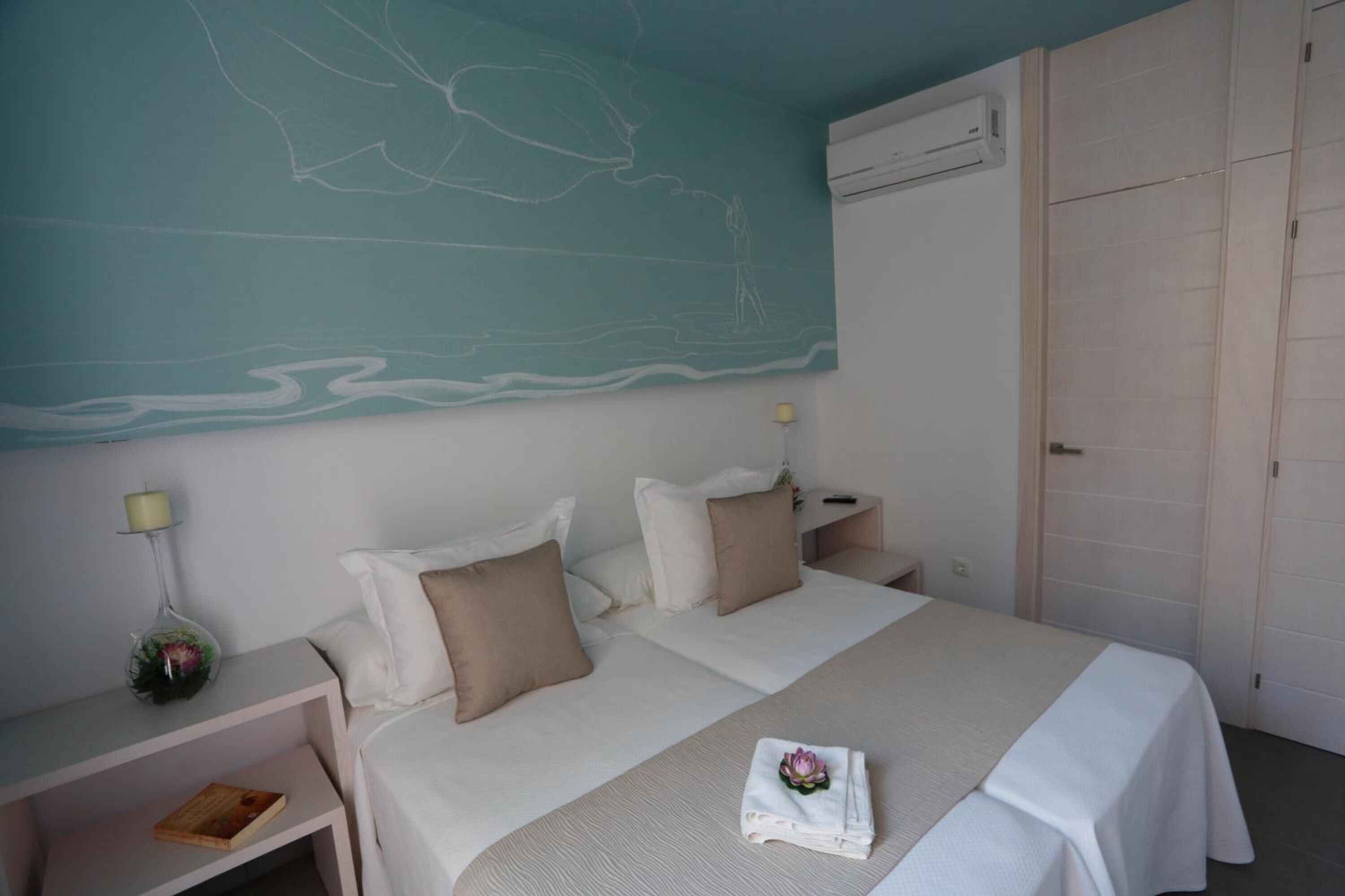A hotel room with two beds, a large wall mural, an air conditioning unit, and a wardrobe.