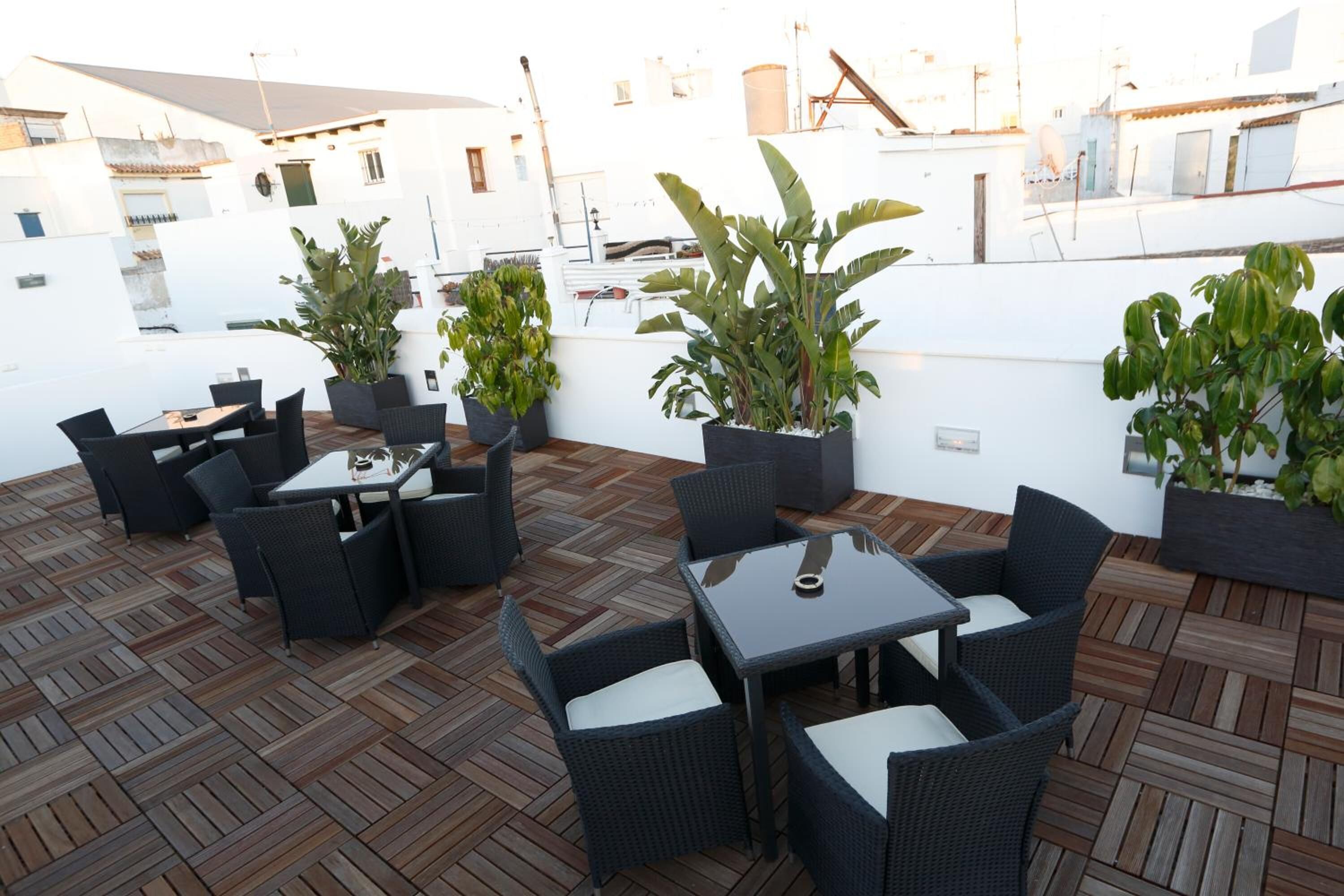 An outdoor patio with wicker furniture and potted plants.
