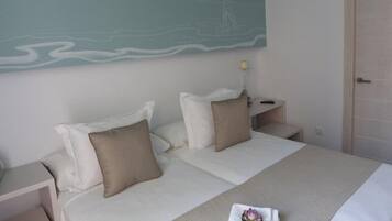 A hotel room with a bed, two bedside tables, a nightstand, a lamp, and a wall with a mural.