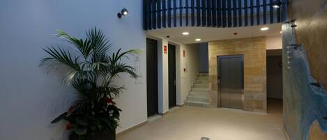 A modern interior with a staircase leading to an upper level, a potted plant, and a glass table.