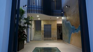 Un interior moderno con una escalera central, un piso de vidrio y un mural en la pared.