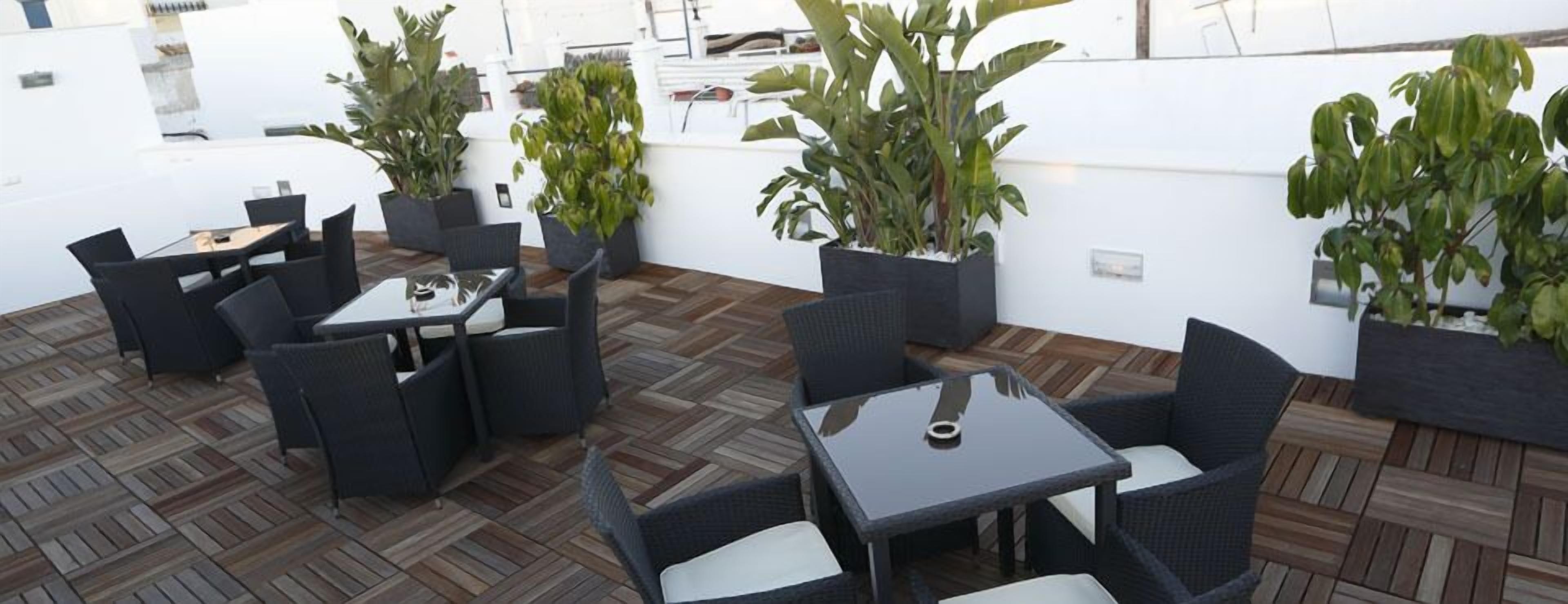An outdoor patio area with wicker furniture and potted plants.