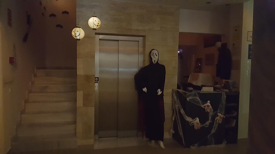 A hotel lobby with a staircase, an elevator, and a mannequin dressed in a black robe.
