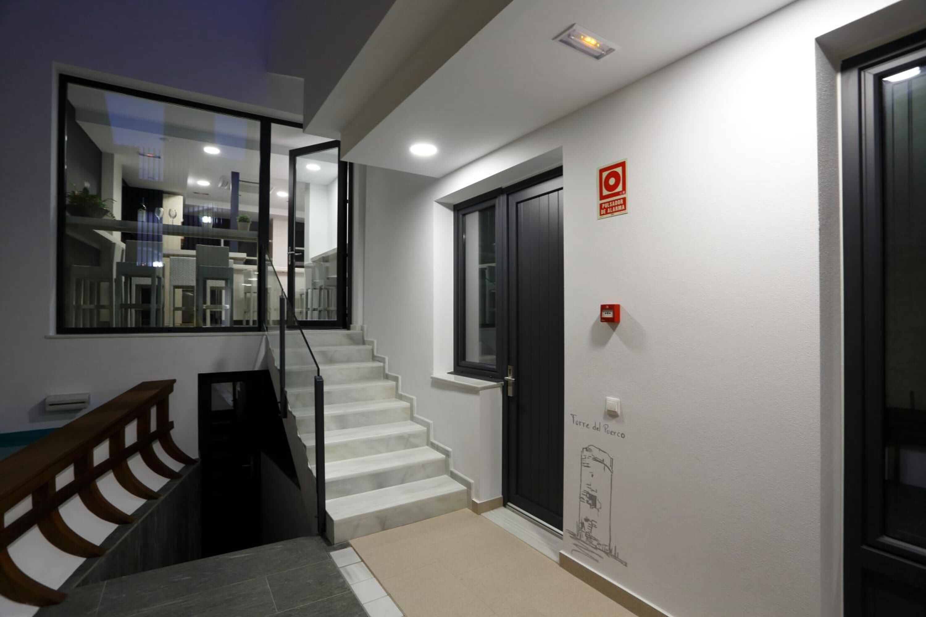 A modern interior with a staircase, a black door, and a window with a view of the interior.