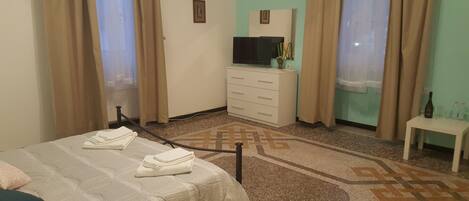 Una habitación de hotel con una cama, un aparador, un televisor y una pequeña mesa con botellas.
