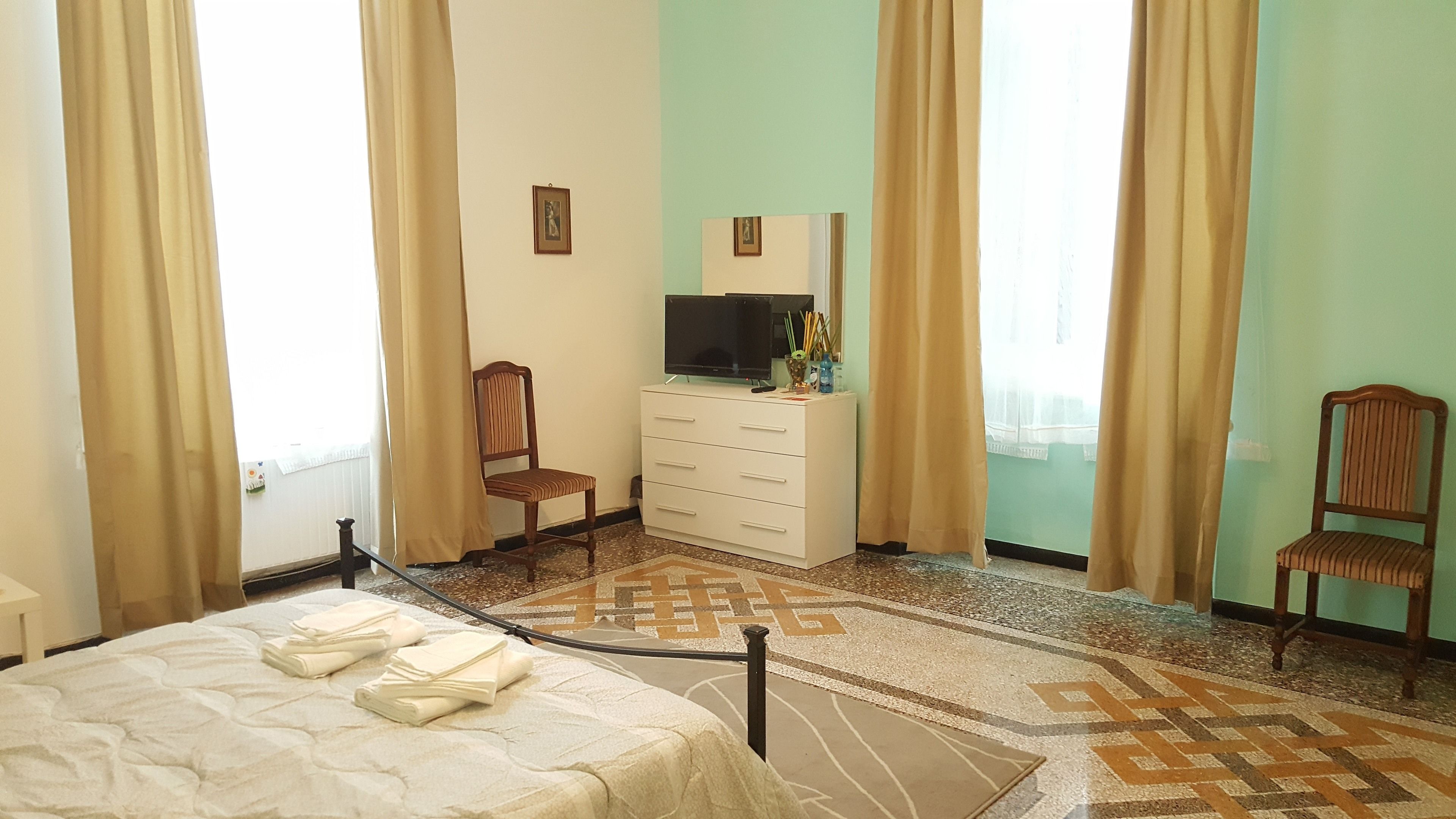 A hotel room with a bed, a desk, a chair, a dresser, and a television.