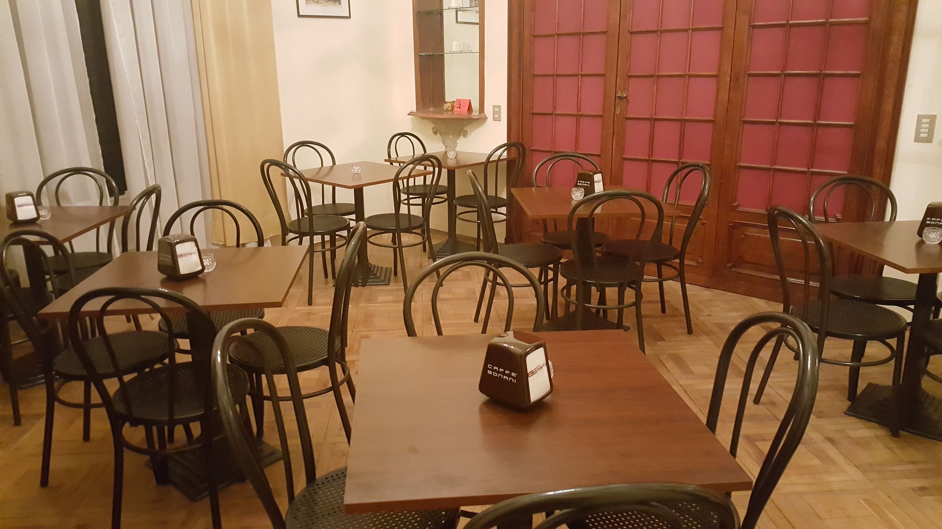 A dining area with multiple tables and chairs, a coffee machine, and a mirror on the wall.