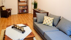 A living room with a grey sofa, a wooden coffee table, a bookshelf, and a painting on the wall. - 1Br Apt In City Center by Minnehaha Lofts (Riga)