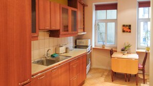 A kitchen with wooden cabinets, a microwave, a sink, and a dining table with chairs. - 1Br Apt In City Center by Minnehaha Lofts (Riga)