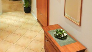A hallway with a wooden cabinet, a potted plant, and a mirror on the wall. - 1Br Apt In City Center by Minnehaha Lofts (Riga)