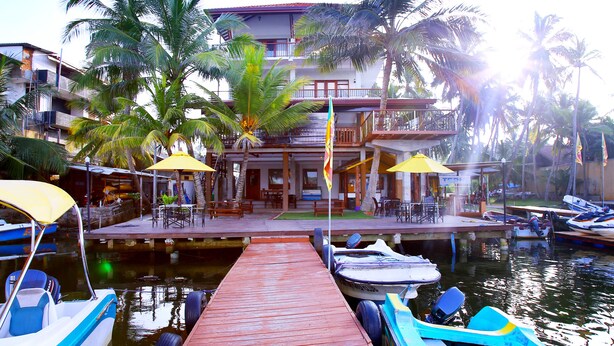 A waterfront hotel with a dock, boats, and palm trees. - Malu Banna (Aluthgama)