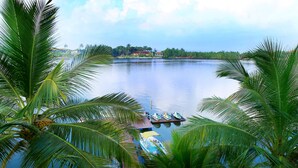 A calm lake with boats docked at a pier, surrounded by lush palm trees. - Malu Banna (Aluthgama)