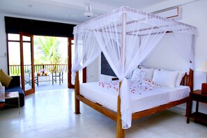 A spacious bedroom with a wooden bed, white bedding, and a canopy.