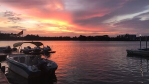 A sunset over a calm body of water with boats docked at a pier. - Malu Banna (Aluthgama)