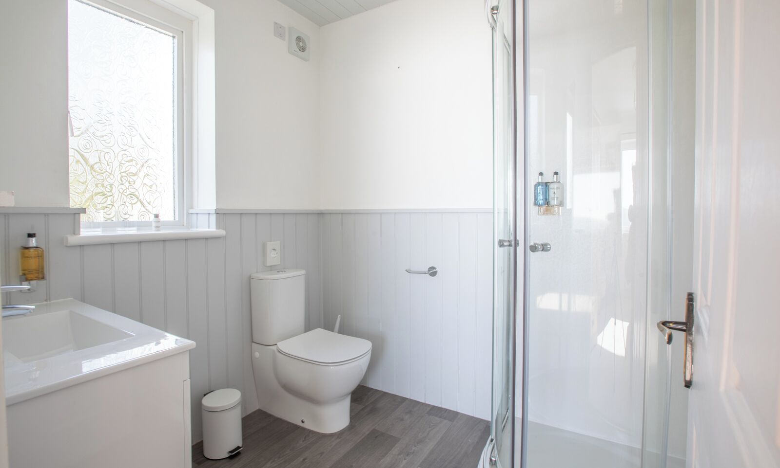 Un baño moderno con inodoro, lavamanos y ducha.