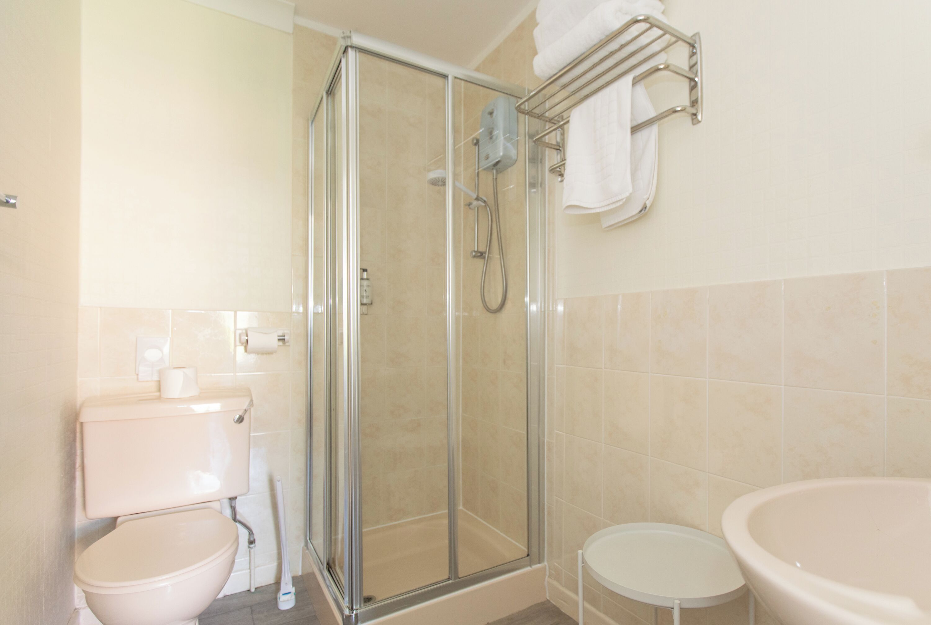 A bathroom with a glass-enclosed shower, a toilet, and a sink.