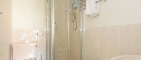 A bathroom with a glass-enclosed shower, a toilet, and a sink.