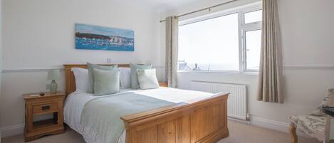 Un dormitorio con una cama de madera, una mesita de noche, una ventana con cortinas y un cuadro en la pared.