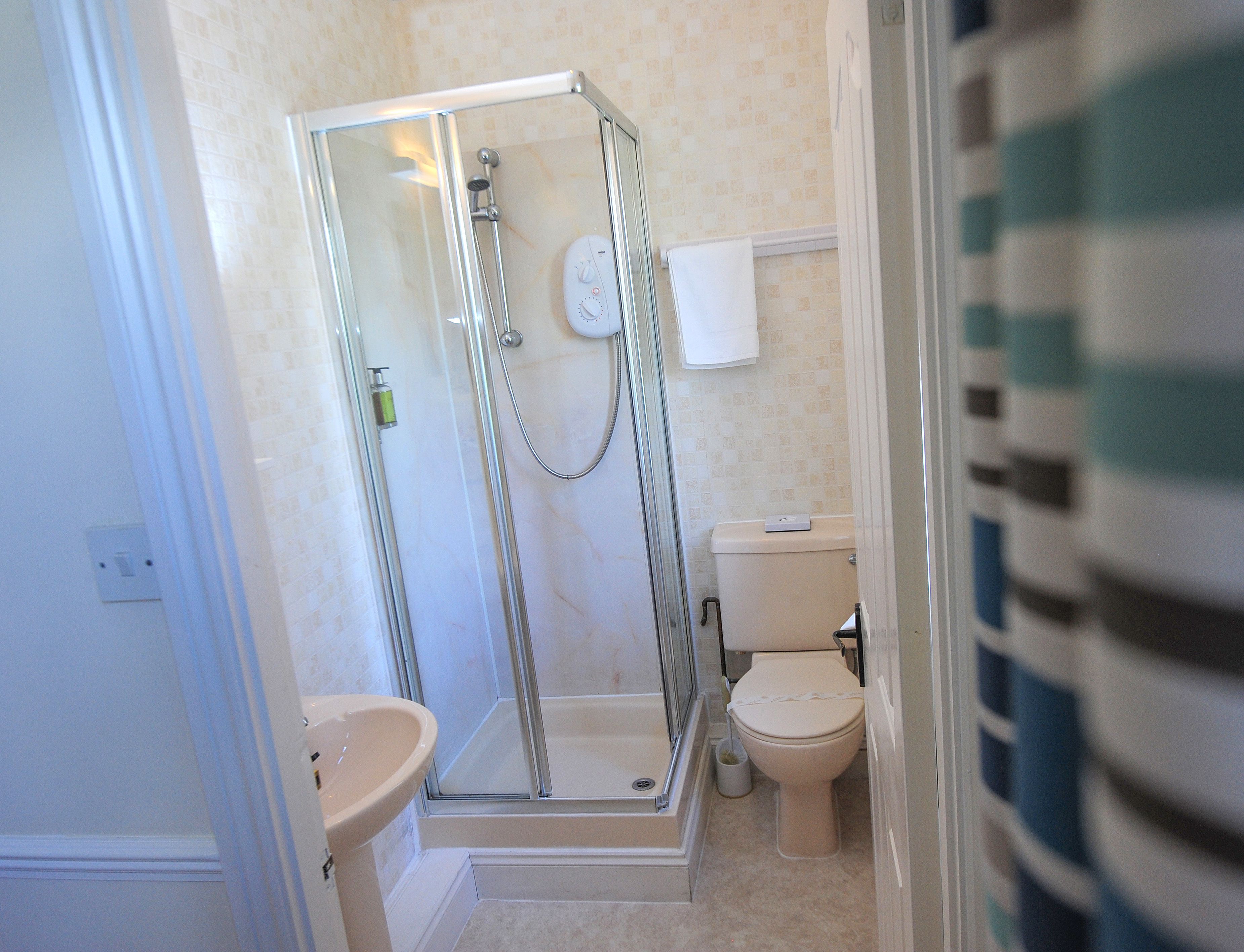 Une salle de bain avec une douche à parois de verre, des toilettes et un lavabo.