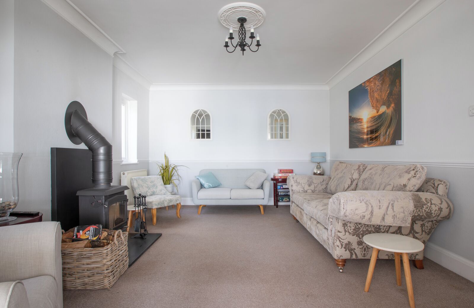 A spacious living room with a fireplace, two sofas, a coffee table, and a chandelier.