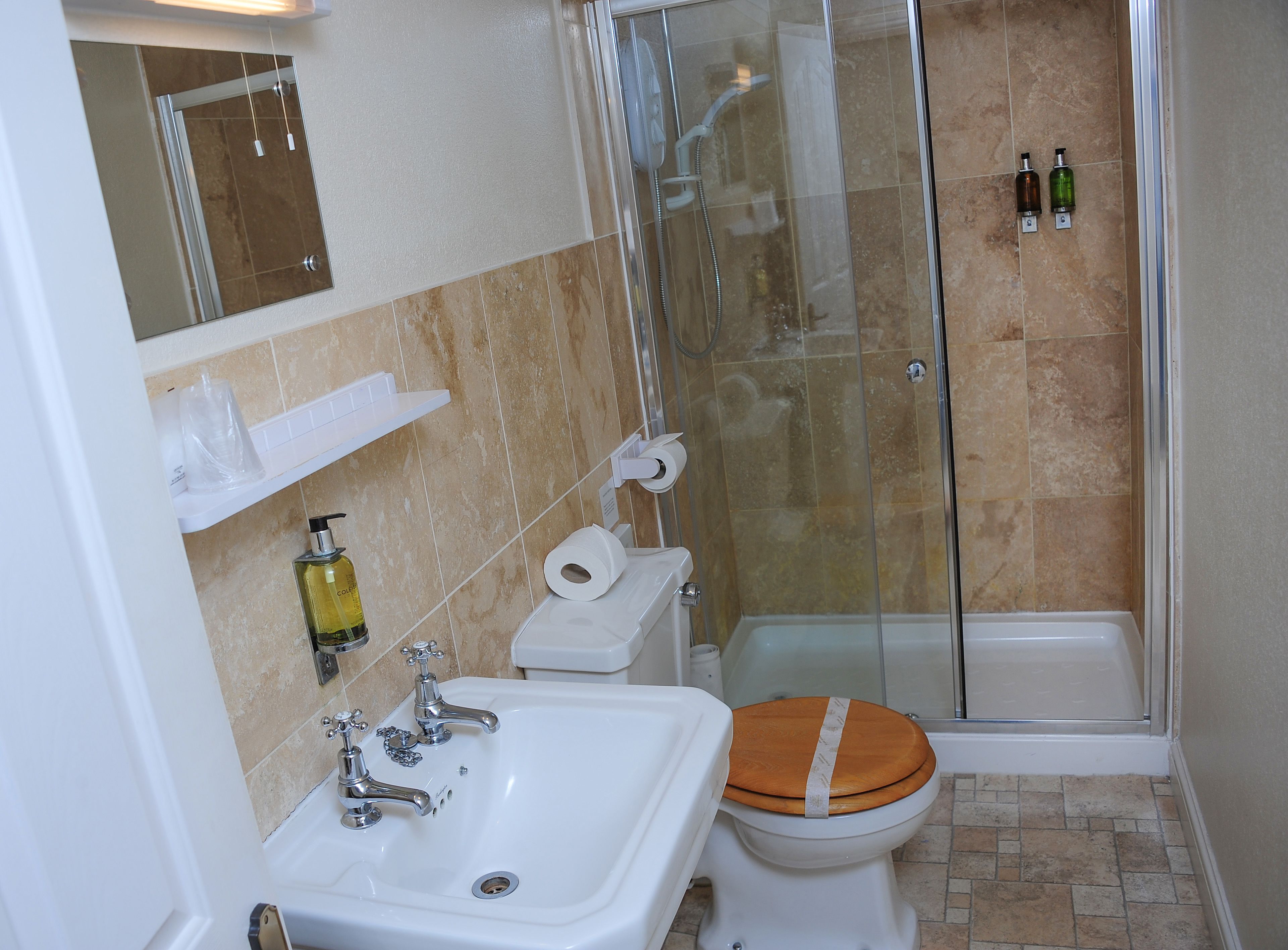 A bathroom with a glass-enclosed shower, a sink, a toilet, and a mirror.