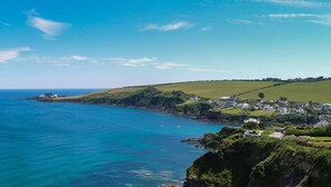 A coastal town with houses along the shoreline, a clear blue sky, and calm sea. - Mevagissey Bay Hotel (St Austell)