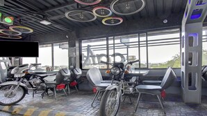 A bicycle rental station with multiple bikes, a seating area, and a large window offering a view of the city. - Treebo Lalaji's Executive (Chhatrapati Sambhajinagar)