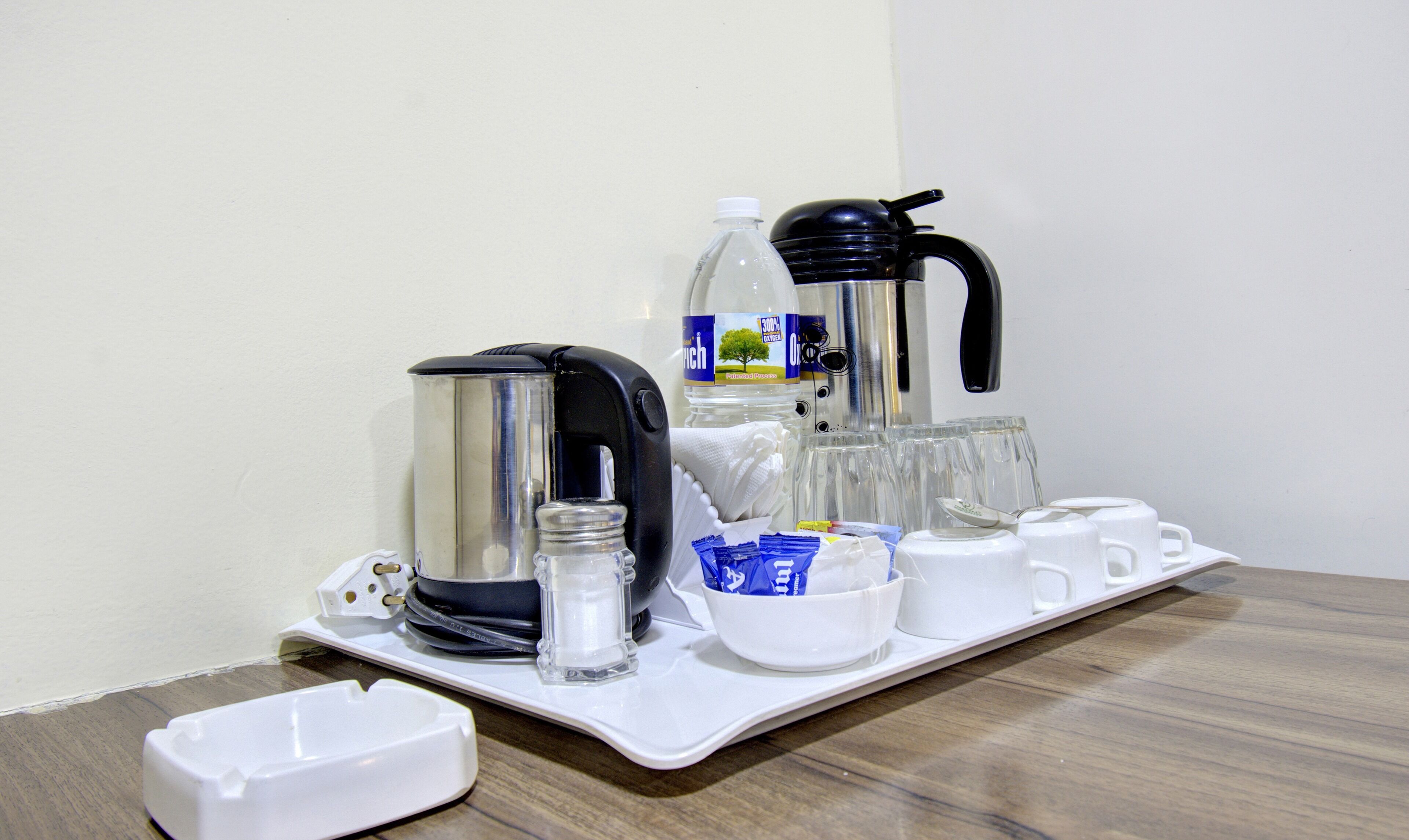 A coffee station with a coffee maker, a water dispenser, cups, and a tray.
