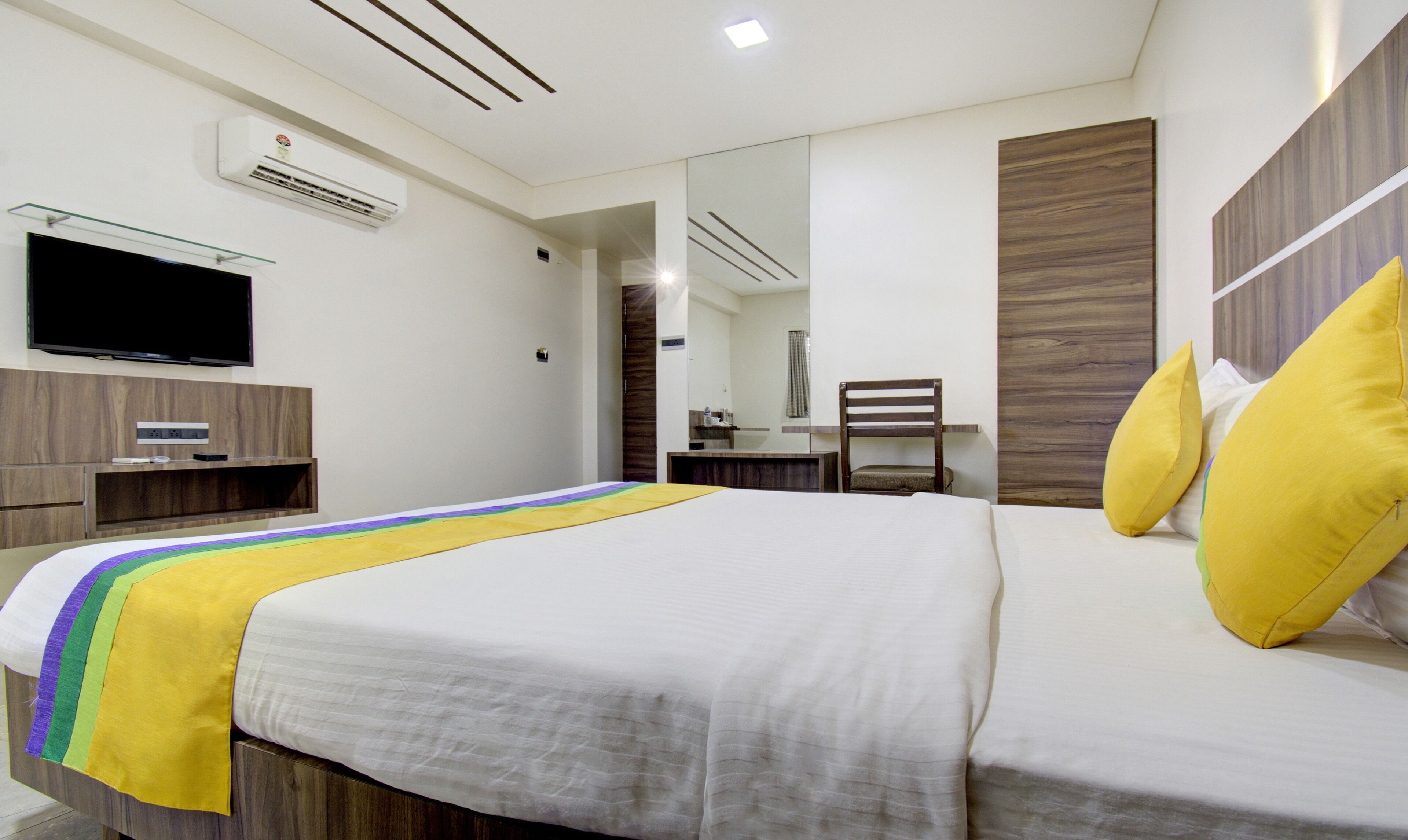 Una habitación de hotel con una cama, televisor, escritorio y silla.