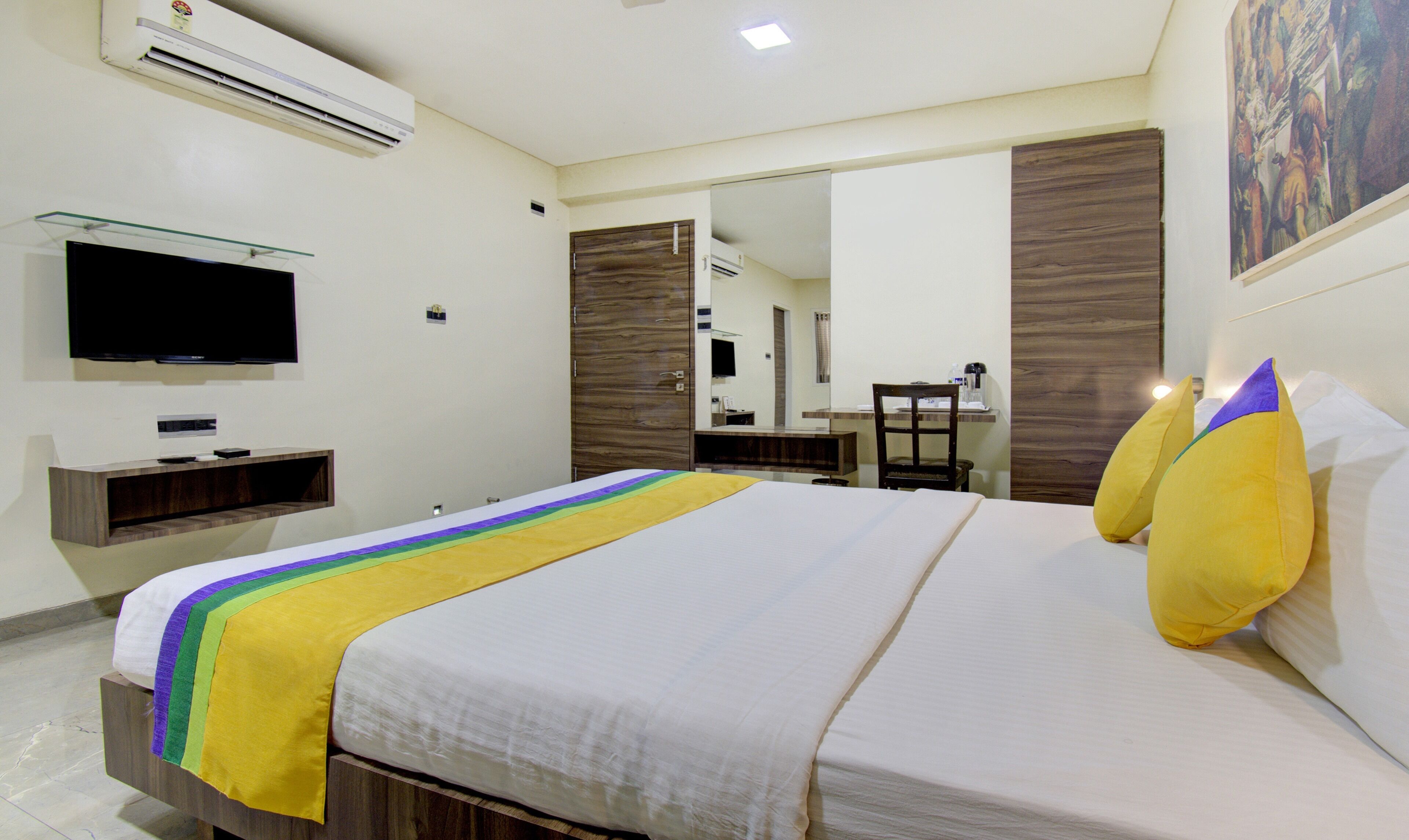 A hotel room with a bed, a TV, a desk, and a mirror.