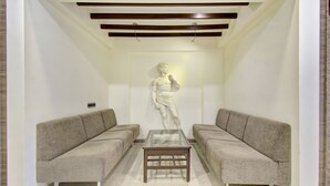 A room with a marble statue, two sofas, and a glass-top table. - Treebo Lalaji's Executive (Chhatrapati Sambhajinagar)