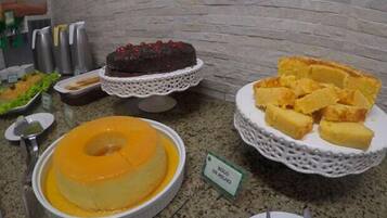 Un buffet proposant divers desserts, notamment un gâteau au chocolat, une crème anglaise et une assiette de pain.