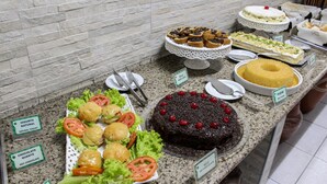 Un bufé con diversos postres y comidas, incluyendo un pastel de chocolate y un pastel bundt.