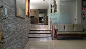Un vestíbulo de hotel con una escalera, un banco de madera y un extintor.