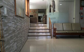 A hotel lobby with a staircase, a wooden bench, and a fire extinguisher.