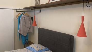 Un dormitorio con una cama, una estantería con fotografías y una lámpara colgante.