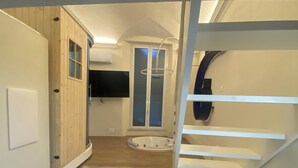A compact, multi-level bathroom with a wooden vanity, a bathtub, and a shower area.
