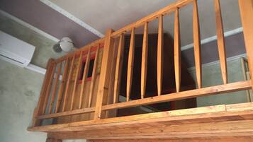 Ein Holzbalkon mit Metallgeländer, einer weißen Decke und einer sichtbaren Klimaanlage.
