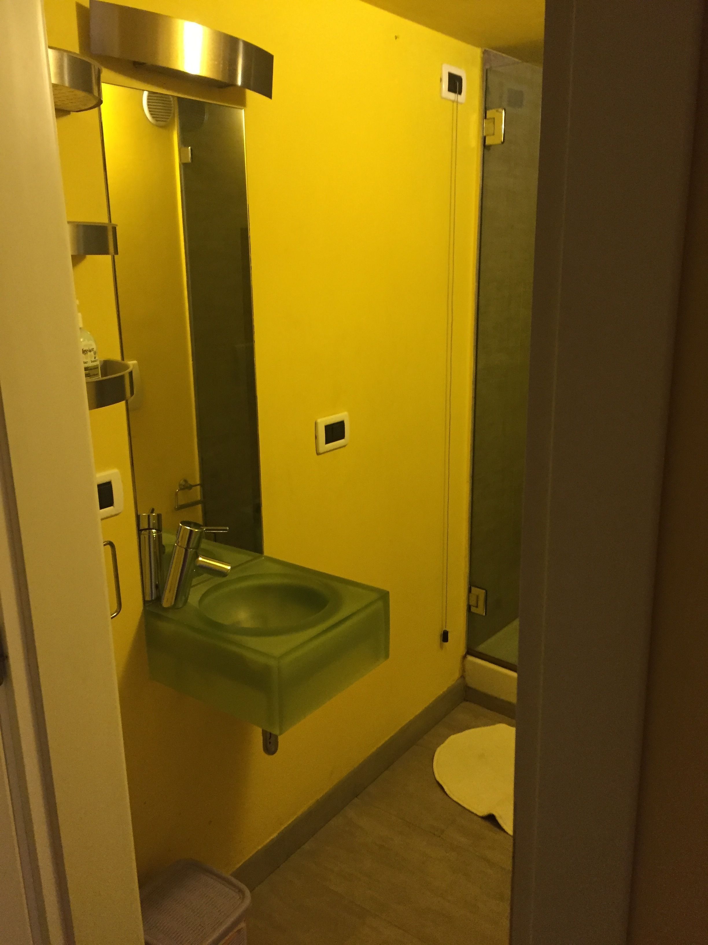 Un baño con un lavamanos verde, un espejo y una ducha.