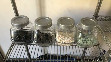A metal shelf with four glass jars containing different colored candies.