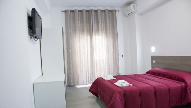 A hotel room with a bed, a desk, and a TV mounted on the wall. - Tiburtina Royal Suites (Rome)