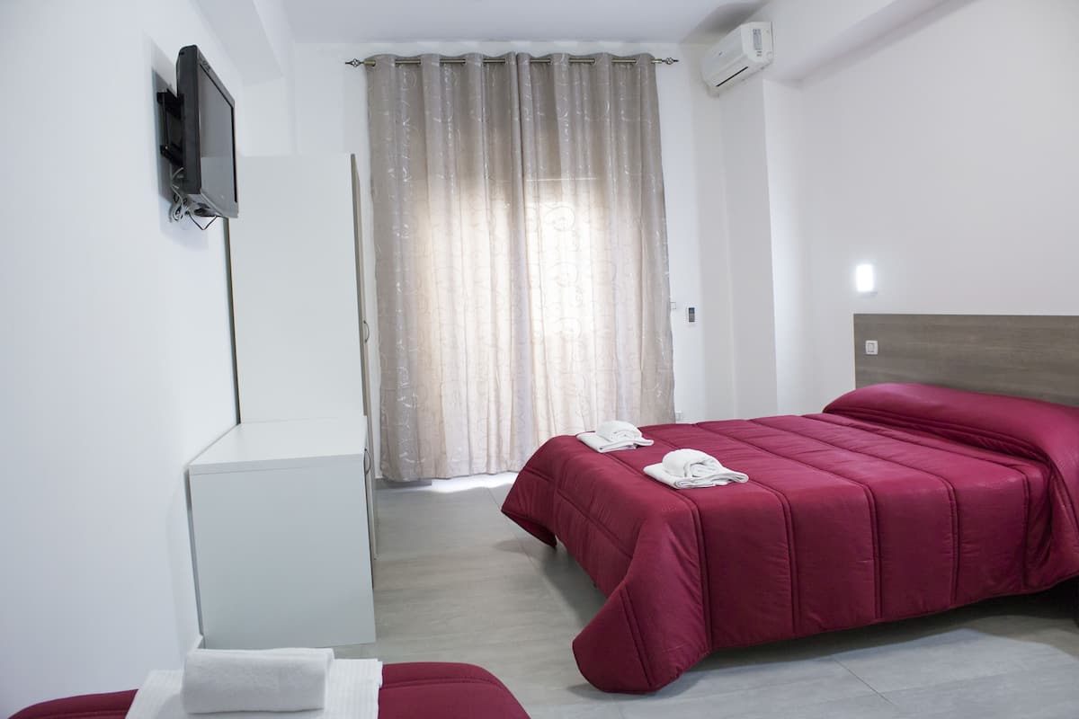 A hotel room with a bed, a desk, and a TV mounted on the wall.