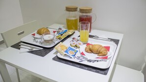 A breakfast tray with croissants, juice, and snacks on a white table. - Tiburtina Royal Suites (Rome)