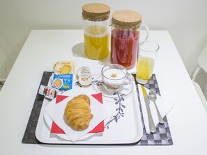 A breakfast tray with a croissant, Nutella, biscotti, and a cappuccino cup. - Tiburtina Royal Suites (Rome)