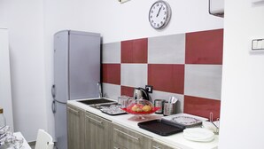 A compact kitchen with a refrigerator, sink, and a clock on the wall. - Tiburtina Royal Suites (Rome)