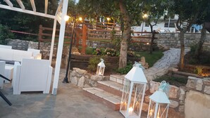 Un patio con mobiliario de mimbre, escalones de piedra y faroles decorativos.