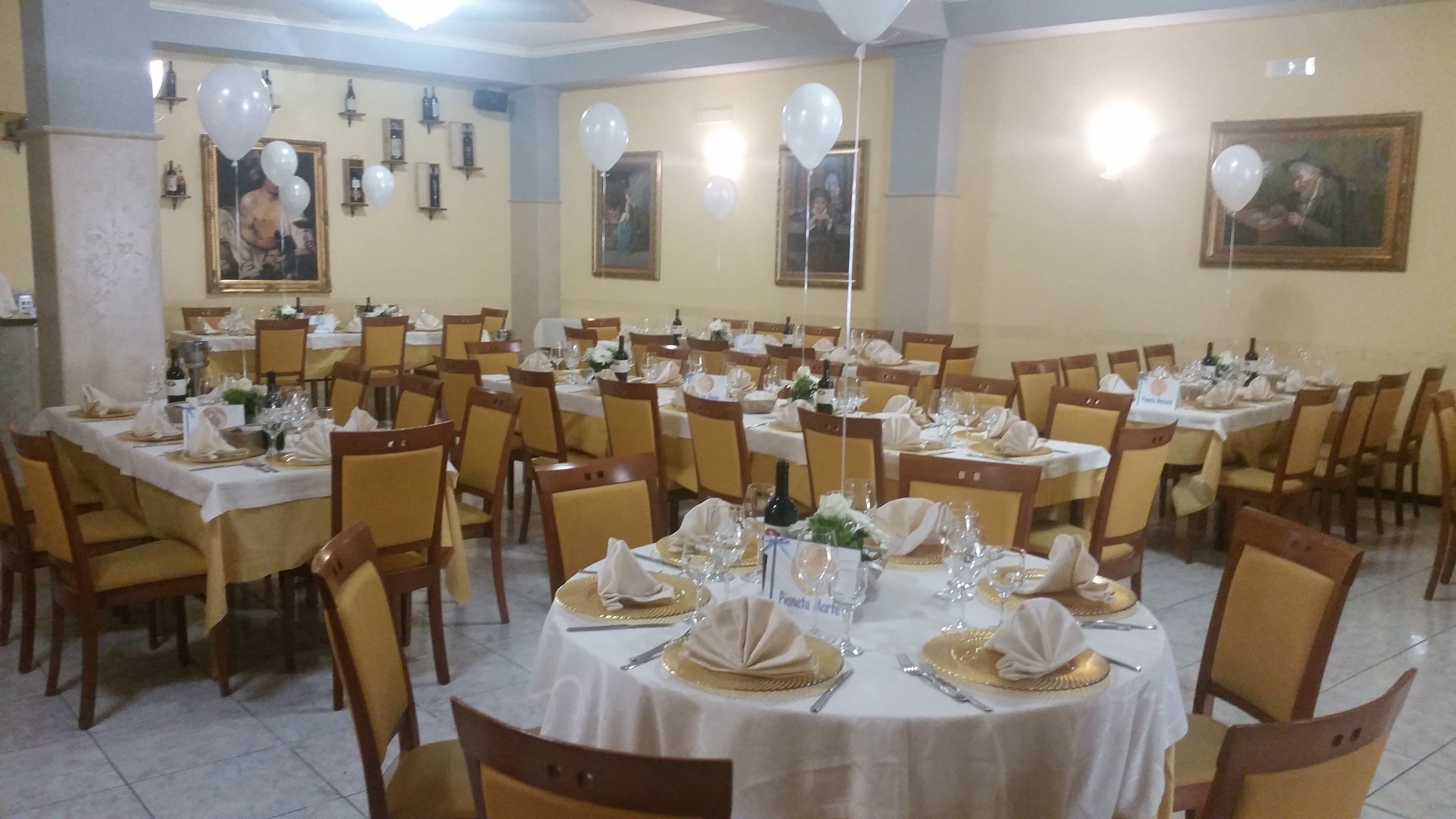 A banquet hall with round tables set for dining, chairs, and white tablecloths.