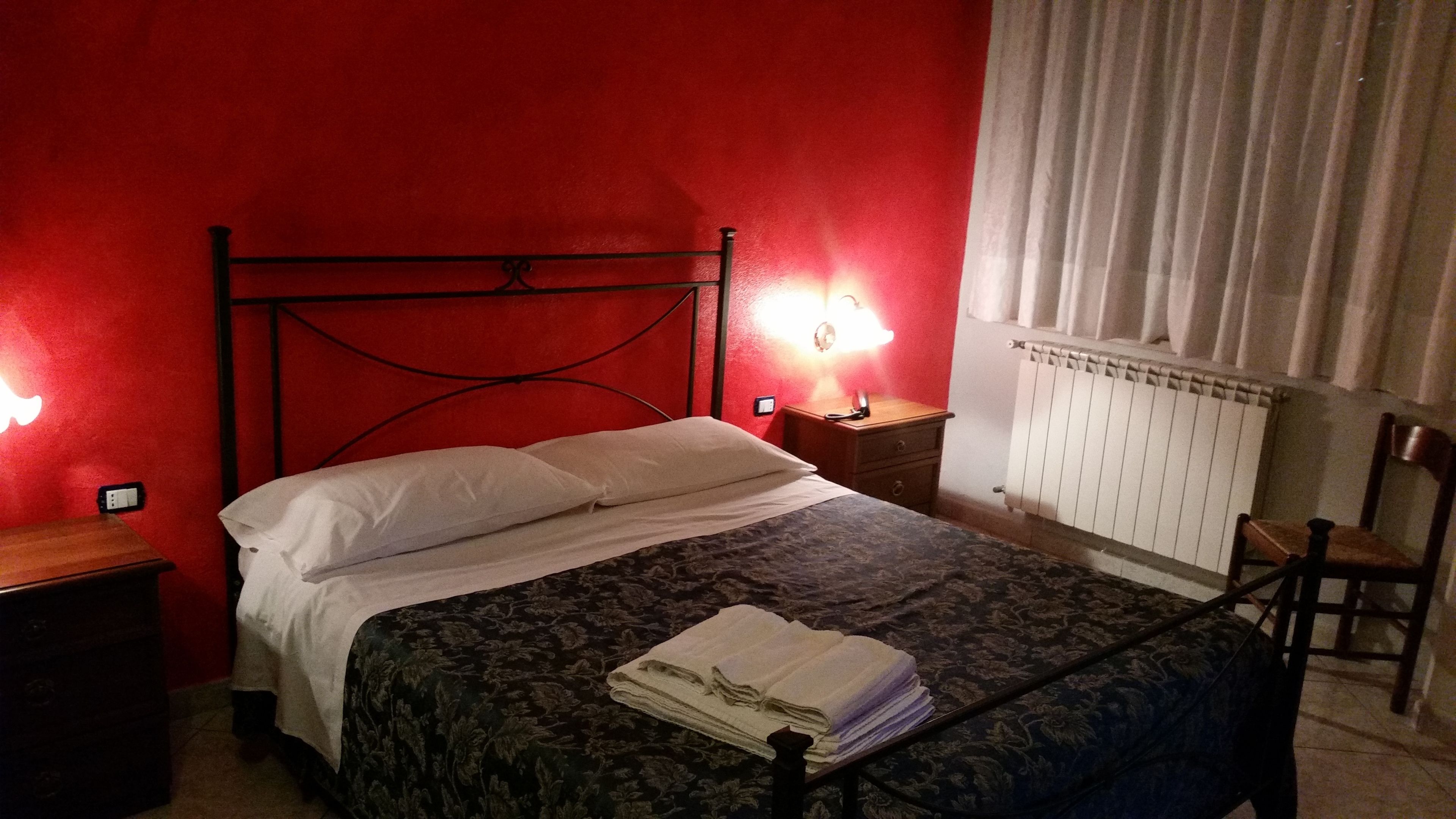 Ein Zimmer mit Bett, Nachttisch, Stuhl und Heizkörper.