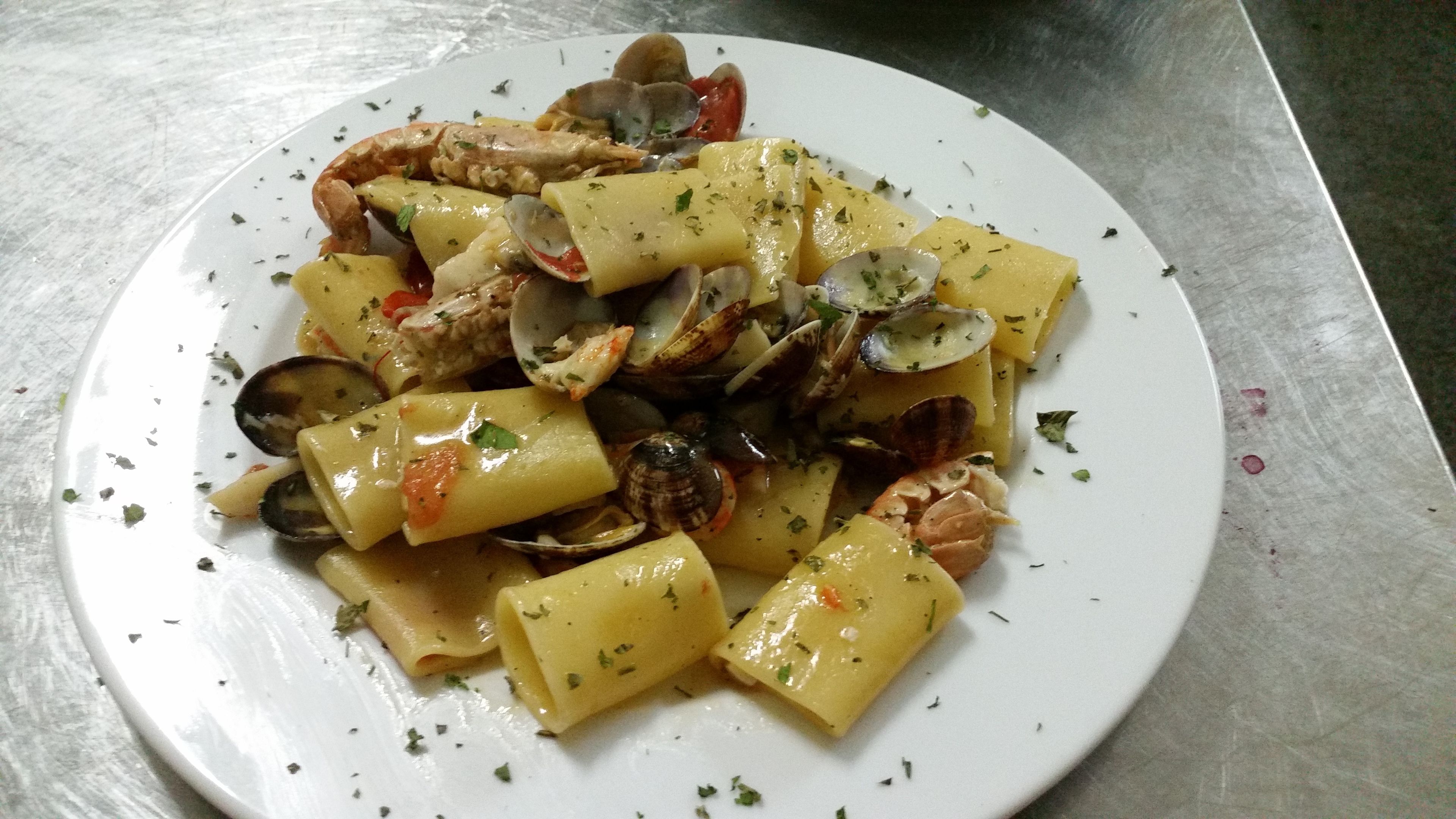 Un plato de pasta con almejas y patatas, adornado con hierbas.