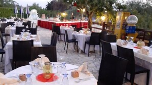 Un área de comedor al aire libre con mesas redondas dispuestas para los comensales, rodeada de sillas.